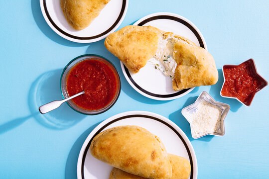 Overhead view of baked pizza puffs served with sauce on table