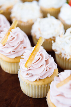 Vanilla cupcakes topped with icing and pineapple slice on table