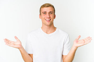 Young caucasian handsome man makes scale with arms, feels happy and confident.