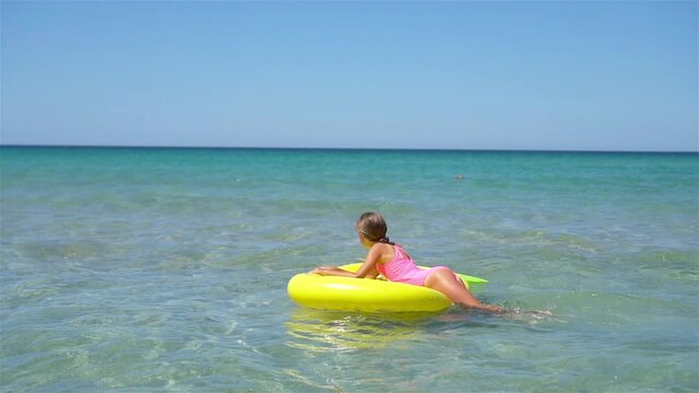 Adorable girl on inflatable air mattress in the sea