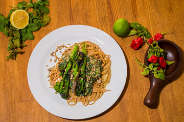 Typical italian plate, pasta spaghetti with Grilled vegetables on a fancy wooden table. Mediterranean food dishes with asparagus, and lemon and peppers decorative around. Food Background