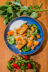 Healthy plate with fried vegetarian tofu and greek halloumi with grilled vegetables and yogurt sauce. Mediterranean food dishes with oriental couscous. Lemons and hot peppers around in decorative way