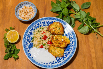Healthy plate with fried vegetables meatballs and yogurt sauce. Mediterranean food dishes with oriental couscous with peppers and garlic. Lemons and peanuts around in decorative way. Food Background