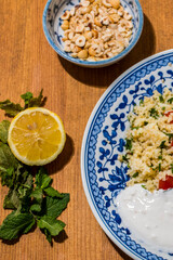Healthy plate with fried vegetables meatballs and yogurt sauce. Mediterranean food dishes with oriental couscous with peppers and garlic. Lemons and peanuts around in decorative way. Food Background