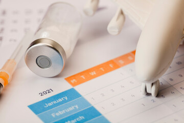 Vaccine vial, syringe and plane, on calendar 2021