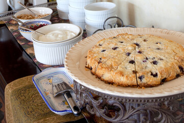 Breakfast buffet in luxury hotel or bed and breakfast serves delightful homemade blueberry scones, cream and coffee 