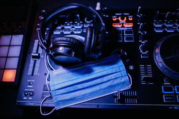 Kopfhörer und Munschutz auf einem DJ Controller