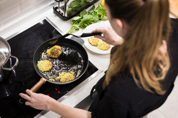 Young charming Swedish woman cooking at home in her kitchen, preparing healthy mediterranean food...