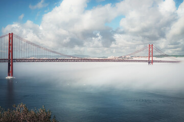 a fantastic photo of a road bridge over a river that hides in clouds and a large fog. bridge April 25 in Portugal in the fog