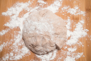 Homemade pizza dough close up on a wooden board with flour. Delicious typical italian recipe.