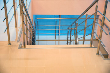 Modern beige office staircase with the chrome handrails