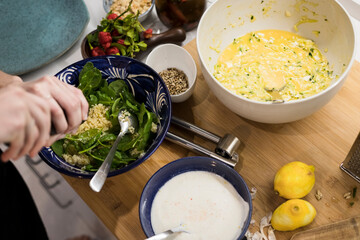 Close up of woman hands garnishing a fresh vegetarian salad with cous cous. Woman cooking in the kitchen at home preparing healthy food. Mediterranean cusine concept.