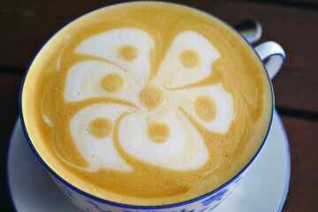 Cup of warm cappuccino coffee with a flower foam design on top