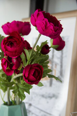 red artificial flowers with green leaves