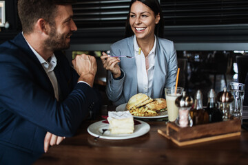 Happy couple man and woman sitting in modern cafe bar or restaurant and drinking coffee.