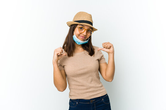 Young latin woman wearing hat and mask to protect from covid isolated on white background feels proud and self confident, example to follow.