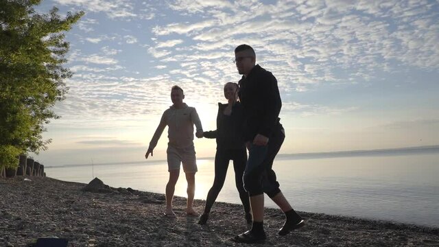 Friends are jumping against the background of dawn and the lake.