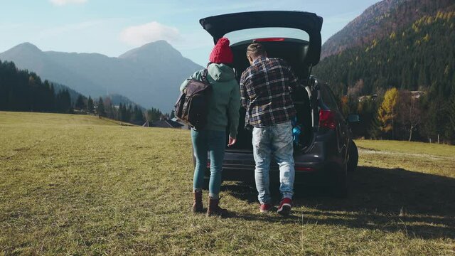 Cute hipster couple of young millennials on their roadtrip after quarantine isolation. Social distancing together. Pretty hikers with bagpack exploring local mountains Travelling by car after pandemic