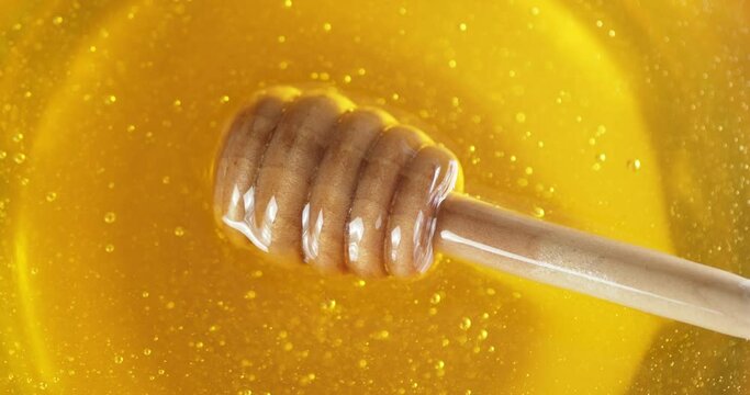 Fresh honey with a wooden spoon slowly rotates. 