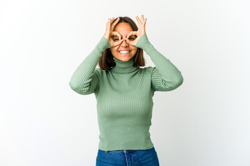 Young mixed race woman excited keeping ok gesture on eye.