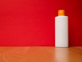 White tube bottle of shampoo, conditioner, hair rinse, mouthwash, on a red background.