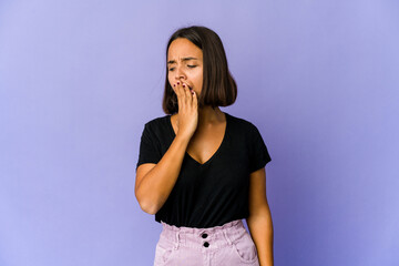 Young mixed race woman yawning showing a tired gesture covering mouth with hand.