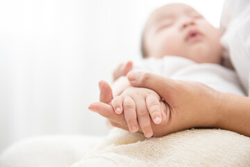 Two hands of the family, a baby, a daughter or son, a mother. Concept of unity, support, protection and happiness. Family hands in bedroom. too soft focus.