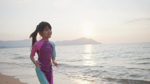 Asian girl running on the beach in the evening with beautiful sunset.