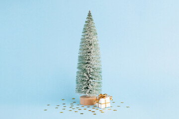 Christmas snowy tree and gift on pastel blue background. Minimal New year concept. Magic pine tree