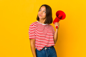 Young hispanic woman holding a megaphone dreaming of achieving goals and purposes