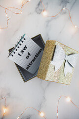 law of attraction, text on notepad inside of present box surrounded by fairy lights