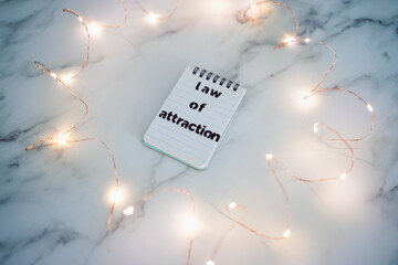 law of attraction, text on notepad surrounded by fairy lights