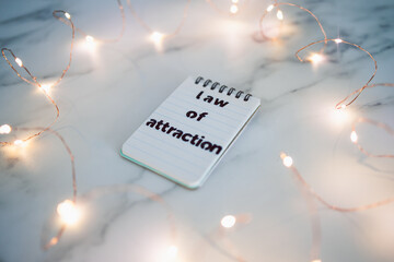 law of attraction, text on notepad surrounded by fairy lights