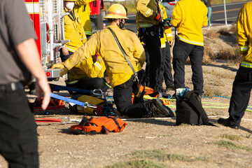 Fireman kneeling at the back of fire truck belaying climbers down side of cliff in a search and rescue effort