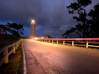 Fototapeta na wymiar night lighthouse with car trail and cloudy sky