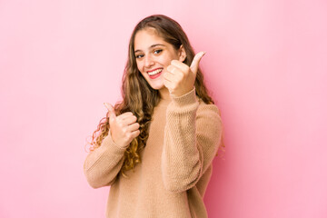 Young caucasian woman raising both thumbs up, smiling and confident.