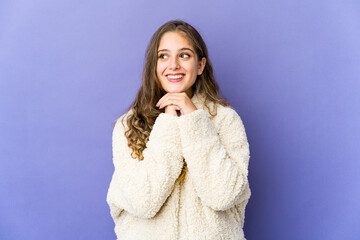 Young caucasian cute woman keeps hands under chin, is looking happily aside.