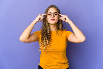 Young caucasian cute woman focused on a task, keeping forefingers pointing head.