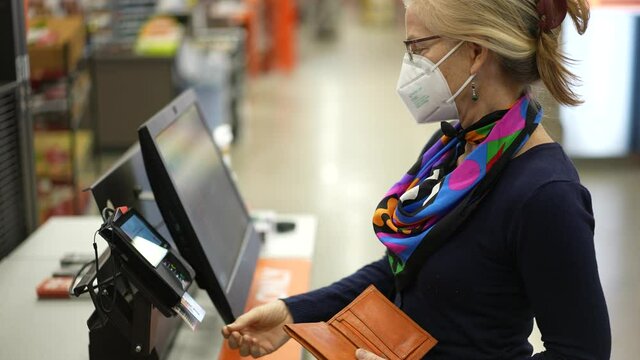 Closeup of woman wearing face mask looking at paint chips in a hardware store. Concept of coronavirus shopping experience.