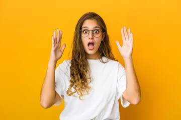 Young caucasian woman celebrating a victory or success, he is surprised and shocked.