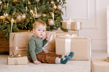 boy sitting under Christmas tree with gift