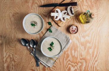 Mushroom cream soup in gray bowls with parsley on wooden background
