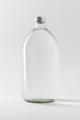 Empty clear glass bottle on off white background