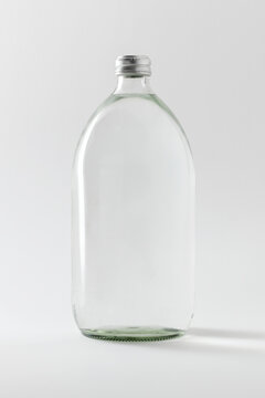 Empty clear glass bottle on off white background