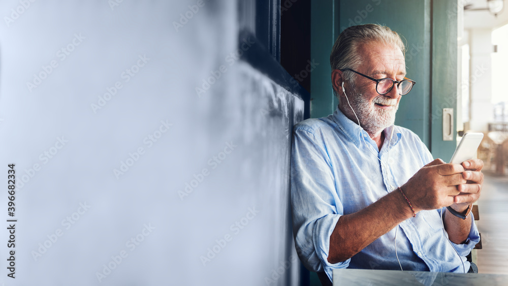 Wall mural elderly man watching online movie from his phone