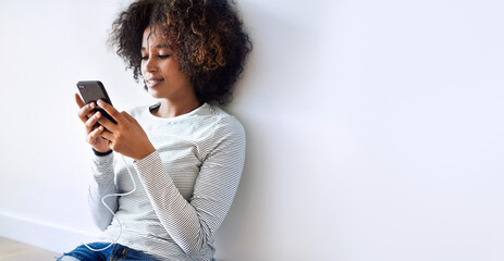 Black woman texting on the floor while charging her phone