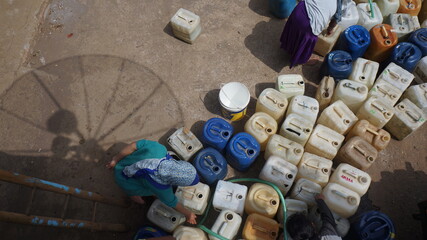 several jerry cans of water were placed on the ground awaiting the arrival of water assistance