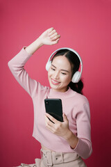Fototapeta premium Portrait of asian woman enjoy listen to song from music streaming isolate on pink background.