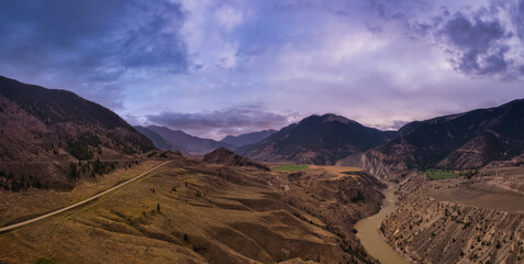 Aerial Panoramic View of a Scenic Highway in the Valley surrounded by Canadian Dramatic Sunset Sky. Mountain Landscape. Taken near Lillooet, British Columbia, Canada.
