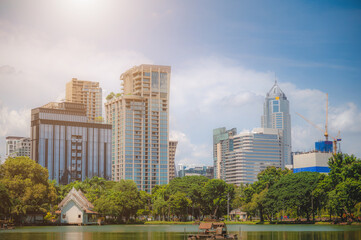 Fototapeta na wymiar Tall building situated on a lake Rich in trees On a clear day At Lumpini Park, Bangkok, Thailand